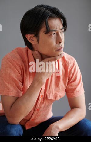 Portrait of young man pondering over problem and looking away Stock Photo