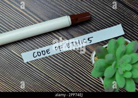 Concept of Code of Ethics write on sticky notes isolated on Wooden Table. Stock Photo