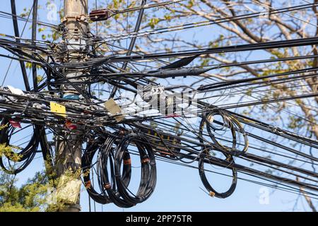 A tangle of electrical wires and telecommunication cables on a city pole Stock Photo