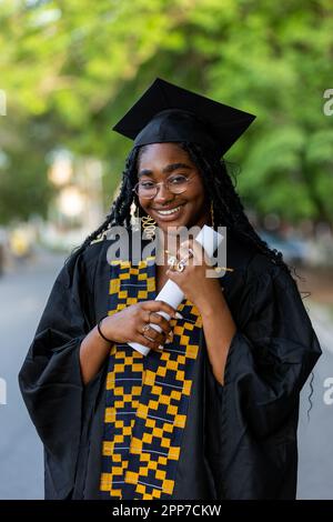 Portrait of Black Female African University Graduate wearing black gown and  cap, holding her diploma certificate, proud of academic achievement and su  Stock Photo - Alamy