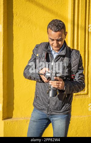 Latino adult man professional photographer takes photos of a field ...
