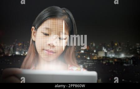A girl scans her face using a tablet to unlock it. Facial recognition or detection. Biometric security system. Cybersecurity tech concept. Business an Stock Photo