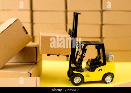 Forklift truck raises cardboard boxes on a yellow background. Cargo ...