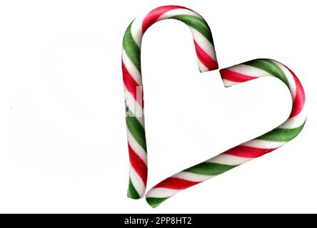 Two colorful candy sticks canes bent on top which together form the shape of a heart on a white background as a concept for love, cordiality and affec Stock Photo