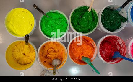 Top view, colorful fabric printing inks in white buckets. Stirring the ink for multicolored tee shirt printing . colorful of ink forprint tee shirt in Stock Photo