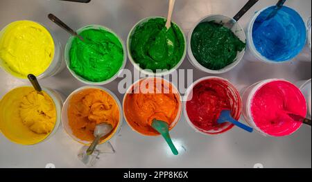 Top view, colorful fabric printing inks in white buckets. Stirring the ink for multicolored tee shirt printing . colorful of ink forprint tee shirt in Stock Photo