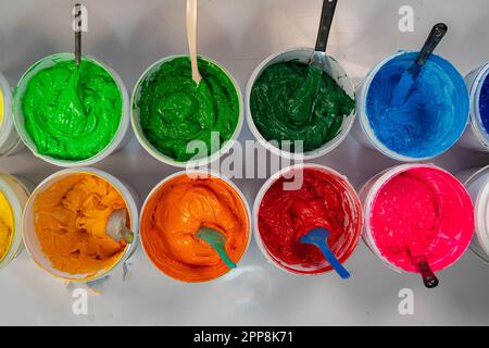 Top view, colorful fabric printing inks in white buckets. Stirring the ink for multicolored tee shirt printing . colorful of ink forprint tee shirt in Stock Photo