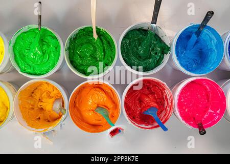 Top view, colorful fabric printing inks in white buckets. Stirring the ink for multicolored tee shirt printing . colorful of ink forprint tee shirt in Stock Photo