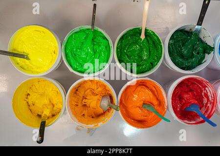 Top view, colorful fabric printing inks in white buckets. Stirring the ink for multicolored tee shirt printing . colorful of ink forprint tee shirt in Stock Photo