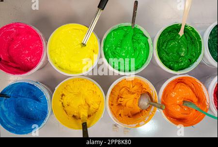 Top view, colorful fabric printing inks in white buckets. Stirring the ink for multicolored tee shirt printing . colorful of ink forprint tee shirt in Stock Photo