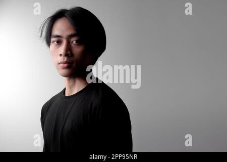Dramatic low light portrait of handsome Asian man looking up. Side light effect Stock Photo
