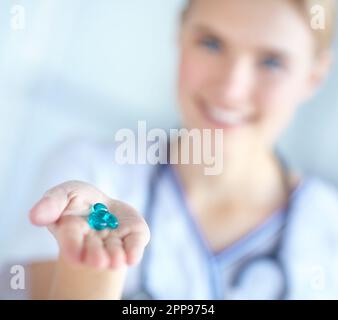 This will help you with the pain...A nurse offering blue pills to the camera - selective focus. Stock Photo