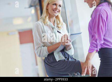 Taking down some important notes. work colleagues writing down notes and discussing ideas. Stock Photo