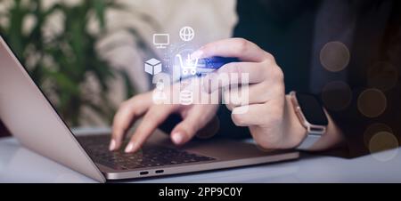 Woman using laptop with online shopping icons on the screen. Bokeh Stock Photo