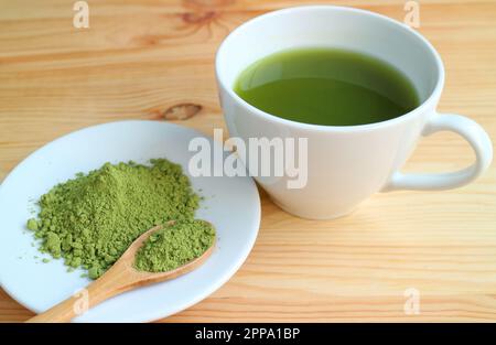 Cup of Hot Matcha Green Tea with a Plate of Matcha Tea Powder on Wooden Table Stock Photo