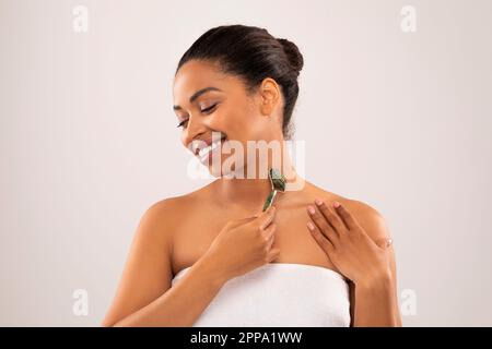 Pretty young black woman massaging neck with gua sha Stock Photo