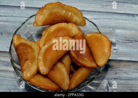 A bowl of qatayef dumplings stuffed and filled with nuts and shredded coconut fried in deep oil and soaked with sugar syrup, Arabic dessert folded pan Stock Photo