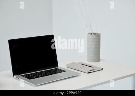 Laptop with empty screen and planner on office table Stock Photo