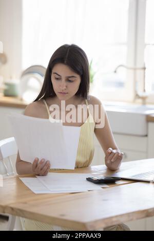 Serious young woman reading domestic residential documents Stock Photo