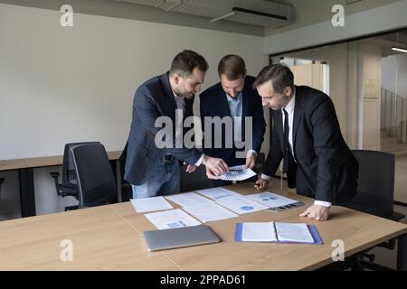 Business coworkers men in formal suits collaborating on marketing plan, Stock Photo