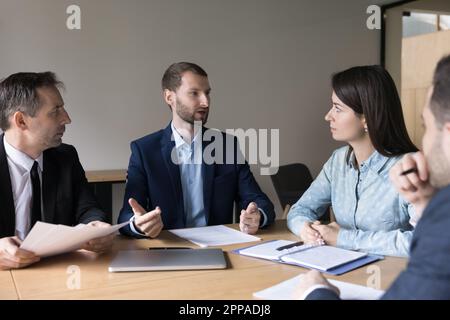 Serious successful young boss, CEO, executive talking to team Stock Photo