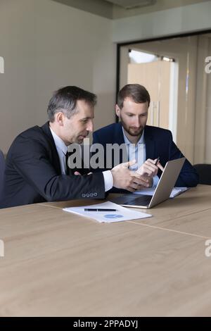 Two serious business colleagues men using laptop at work table Stock Photo