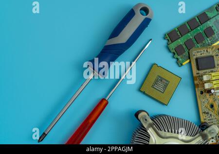 Computer chip of PC motherboard and screwdriver at repair workshop. Top view CPU chipset on blue background. Electronic components. Computer hardware. Stock Photo