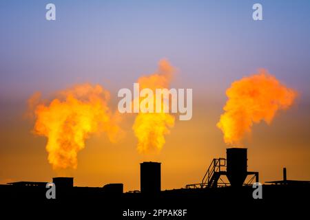 Dark smoke comming from the chimneys of an old factory Stock Photo