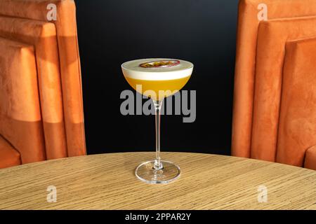 Summer cocktail garnished with passion fruit. rich yellow cold beverage on bar terrace. Stock Photo