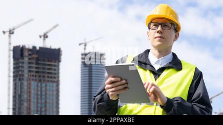 Engineer with a digital tablet on the background of a building under construction. High quality photo Stock Photo