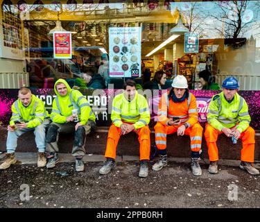 Belfast County Antrim Northern Ireland, December 19 2018 - workmen having a lunch break sitting outside a café full of people in Belfast's city centre Stock Photo