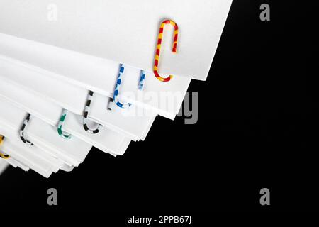 Stacks of papers with multicolored paper clips on a dark background Stock Photo