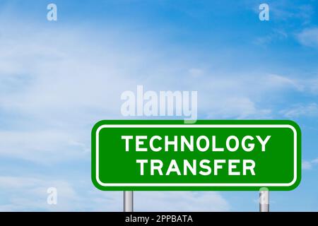 Green color transportation sign with word technology transfer on blue sky with white cloud background Stock Photo