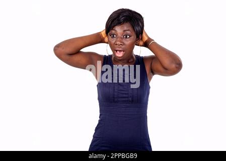 portrait of a beautiful amazed young woman with open mouth holding hands on head. Stock Photo