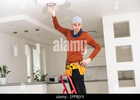 Electrician man working on exterior light, install LED replacement lamp at home. Maintenance concept. Stock Photo