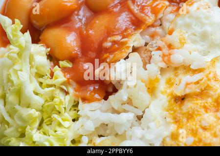 fried eggs with beans in tomato and salat with cabbage on a plate on an isolated background for lunch without mea Stock Photo