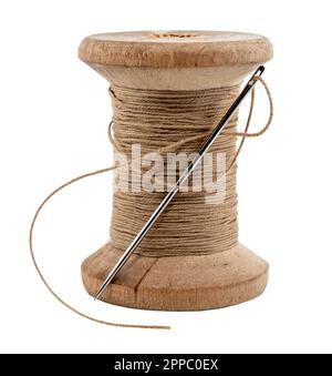 Old wooden spool of thread and needle on a white background. Sewing accessories Stock Photo
