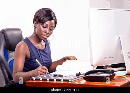 portrait of a concentrated young businesswoman working in the office while writing notes in the document. Stock Photo