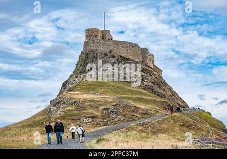 View of Lindisfarne Castle on hill with people walking, Holy Island of Lindisfarne, Northumberland, England, UK Stock Photo