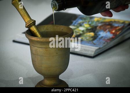 Pouring olive oil in copper mortar and pestle Stock Photo