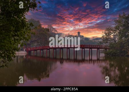 HANOI, VIETNAM - JANUARY 2, 2023: The Red Bridge in public park garden with trees and reflection crossing the Hoan Kiem Lake in Downtown Hanoi Stock Photo