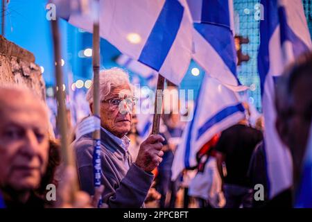 Tel Aviv, Israel. 22nd Apr, 2023. A protestor holds the Israeli flag during an anti reform demonstration in Tel Aviv. Hundreds of people rallied for the 16th straight week Saturday against Netanyahu's coalition judicial overhaul plans. At the main protest in Tel Aviv, members of bereaved families set up a makeshift memorial with candles to commemorate fallen soldiers. The families urged politicians to stay clear of cemeteries on Memorial Day, which begins Monday at nightfall and ends Tuesday evening with the start of Independence Day. Credit: SOPA Images Limited/Alamy Live News Stock Photo