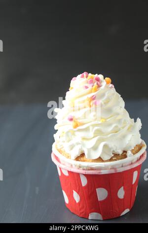 CC cupcake with a white cream cap and colored sprinkles. Birthday cake cake on a black gray background with space for text. The benefits of harm to sw Stock Photo