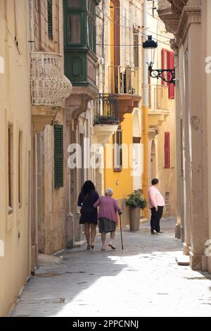 Rabat, Malta - November 13, 2022: People walking the pedestrian narrow street, from behind Stock Photo