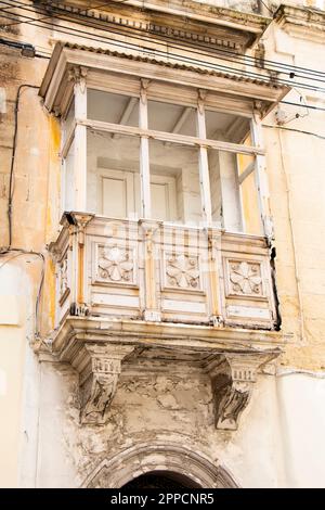 Rabat, Malta - November 13, 2022: Weathered white typical maltese ornate closed wooden balcony, close up Stock Photo