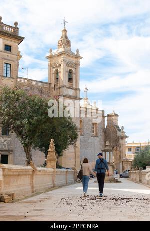 Rabat, Malta - November 13, 2022: Restored limestone pathway passage leading to St Paul's basilica and a main square, with young couple walking hand i Stock Photo