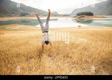 Man doing handstand on dry grass Stock Photo