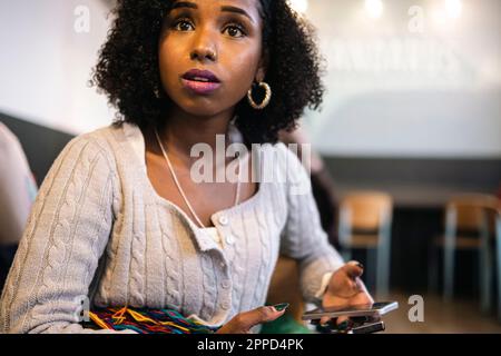 Worried woman with curly hair holding smart phone Stock Photo