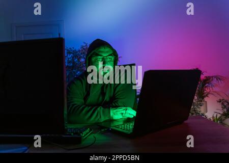 Hacker with computers on desk at home Stock Photo