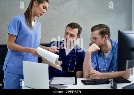 Female doctor discussing over documents with colleagues Stock Photo